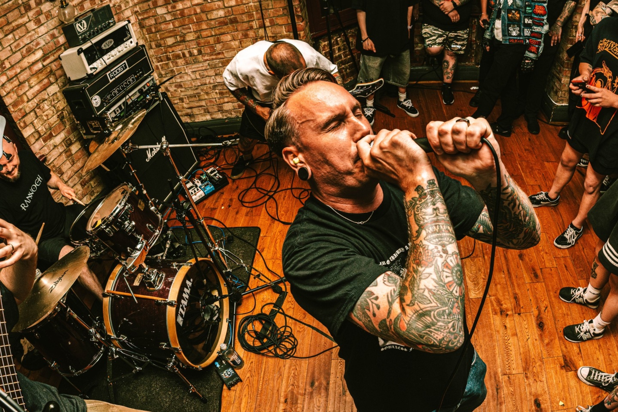 Photograph shot with a fisheye lens of a band performing, surrounded by a semicircle crowd in front.