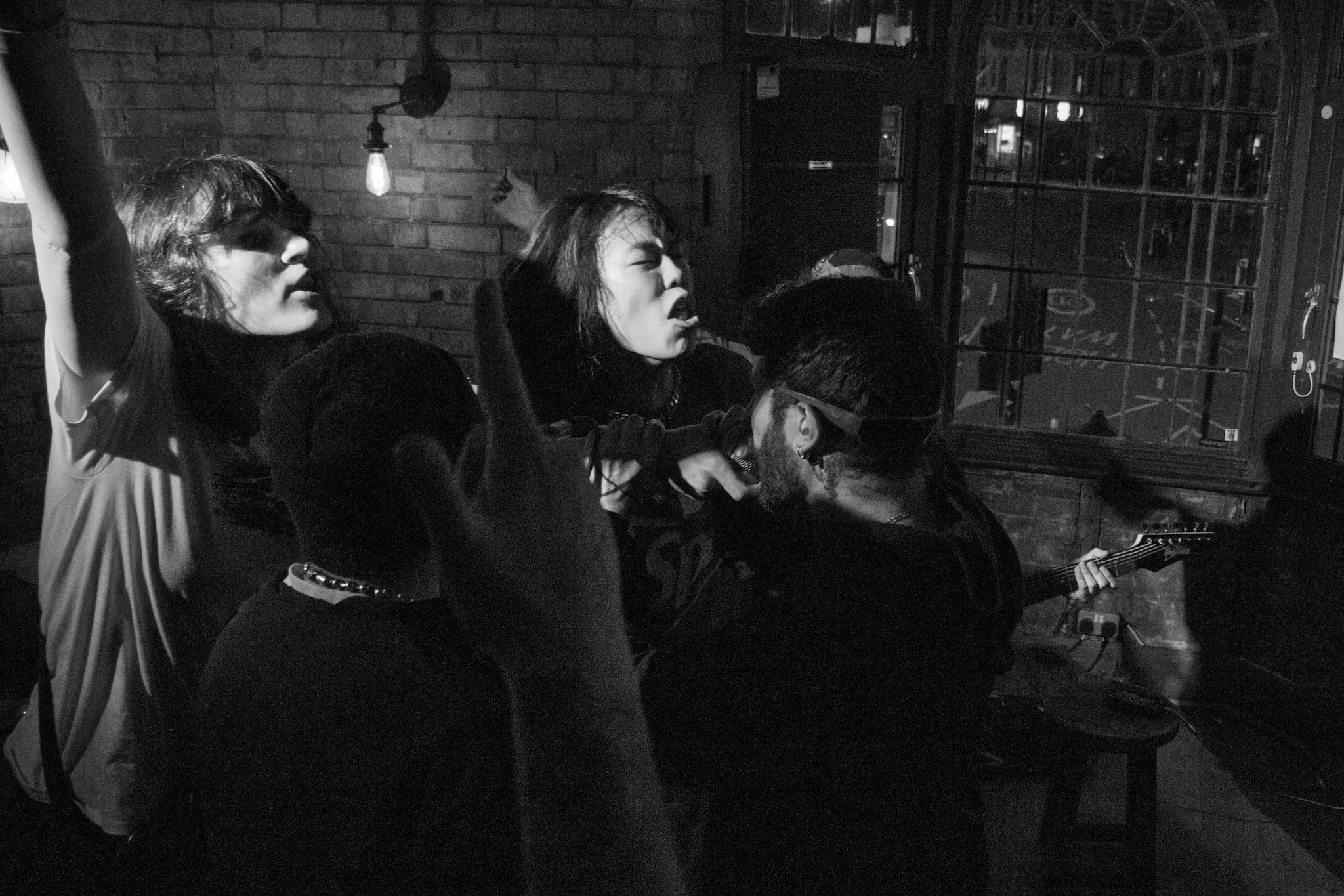 Black & white photograph of a crowd of people yelling into a microphone.